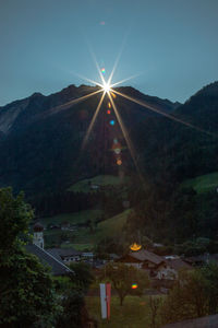 Scenic view of illuminated building by mountain against sky