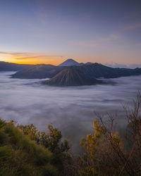 Scenic view of landscape against cloudy sky during sunset