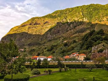 Scenic view of green landscape and houses against sky