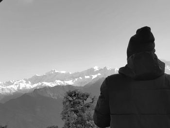 Rear view of young man against snowcapped mountains