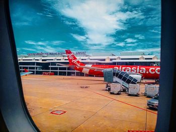 Graffiti on airport runway against sky seen through window