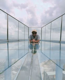 Man standing on glass against sky