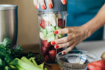 Close-up of a glass blender bowl filled with berries, banana and celery pieces. 