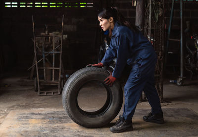 Female mechanic holding tire at garage