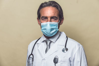 Portrait of smiling doctor wearing mask against colored background