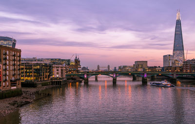 Bridge over river with buildings in background at sunset