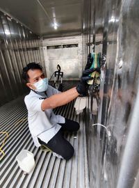 Side view of a young man brushing steel wall