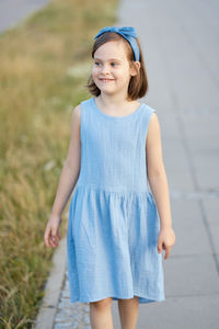 Portrait of young woman standing on footpath