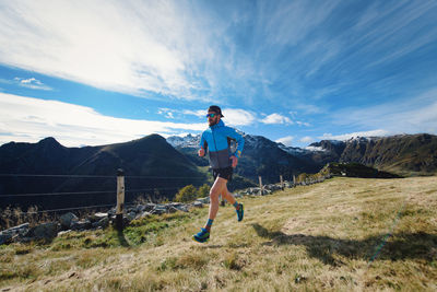 Rear view of man standing on mountain against sky