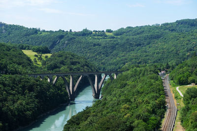 Bridge over river amidst trees against sky