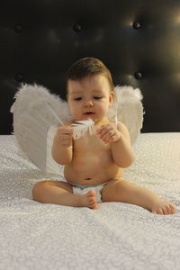 Cute baby girl sitting on sofa at home