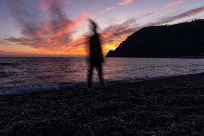 Silhouette of man standing on beach during sunset