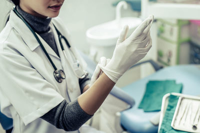 Midsection of female doctor wearing protective gloves in clinic