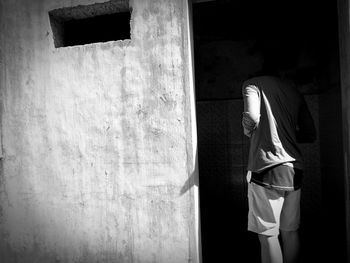 Rear view of woman standing against wall