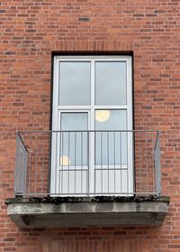 Low angle view of window on brick wall with small balcony.