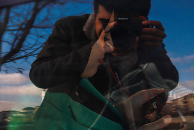 Midsection of man photographing against sky