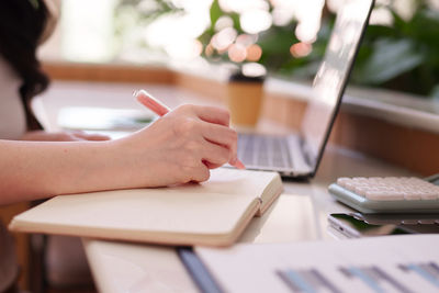 Midsection of woman using laptop on table