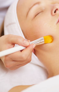 Cropped image of beautician applying gel on face
