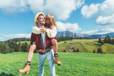 Rear view of couple standing on mountain against sky