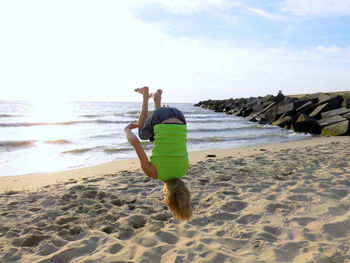 Boy jumping upside on beach