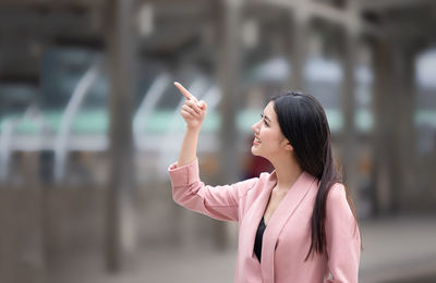 Woman pointing while standing outdoors