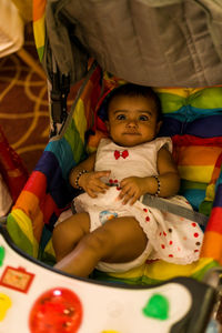 Portrait of cute baby girl relaxing on bed at home