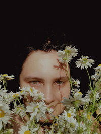 Close-up portrait of woman against black and white flowering plants