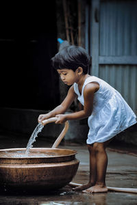 Side view of girl filling water in container