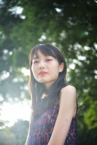 Portrait of teenage girl standing against trees