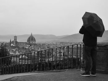 Rear view of man standing by cityscape against sky