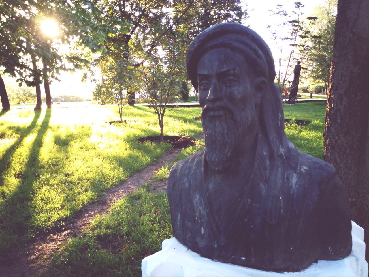 tree, statue, sculpture, human representation, park - man made space, grass, sunlight, one person, day, art, nature, park, art and craft, tranquility, field, outdoors, standing, growth, creativity