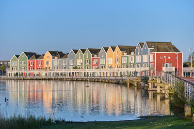 Buildings by river against clear sky