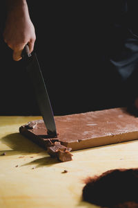 Midsection of man holding knife on chocolate