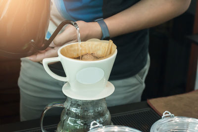 Midsection of man holding coffee cup on table