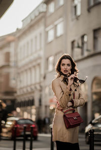 Fashionable woman standing against building in city