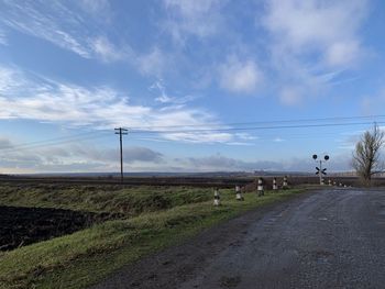 Road amidst field against sky