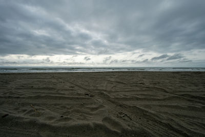 A dramatic stormy and cloudy sky over a dark colored beach