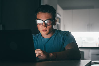 Portrait of young man using laptop at office