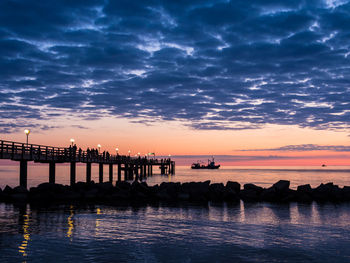 Pier on sea against sky during sunset