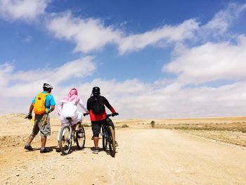 Rear view of friends traveling at desert against sky