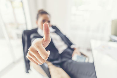 High angle close-up of businesswoman gesturing thumbs up at office