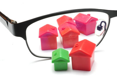 Close-up of eyeglasses amidst model homes over white background