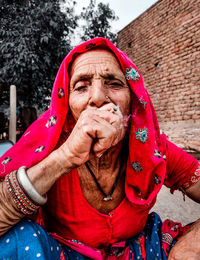 Portrait of woman in red clothes sitting outdoors while smoking