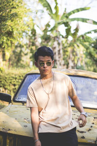 Portrait of mid adult man wearing sunglasses against car 