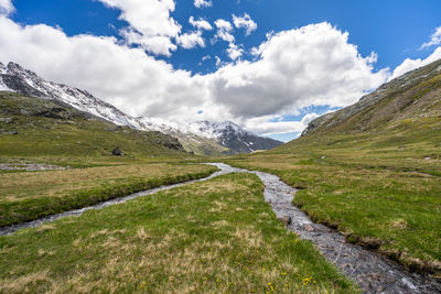 Scenic view of road amidst field against sky