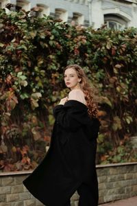 Side view portrait of young woman standing against plants