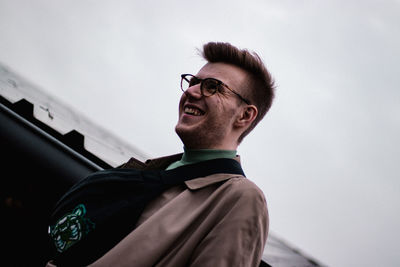 Young smiling man wearing eyeglasses looking away while standing outdoors