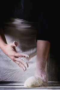 Midsection of person kneading dough