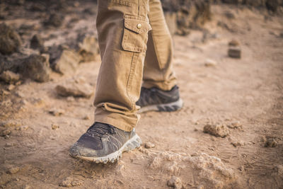 Low section of man wearing standing on dusty field