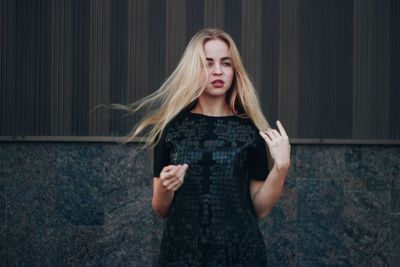 Young woman standing against wall